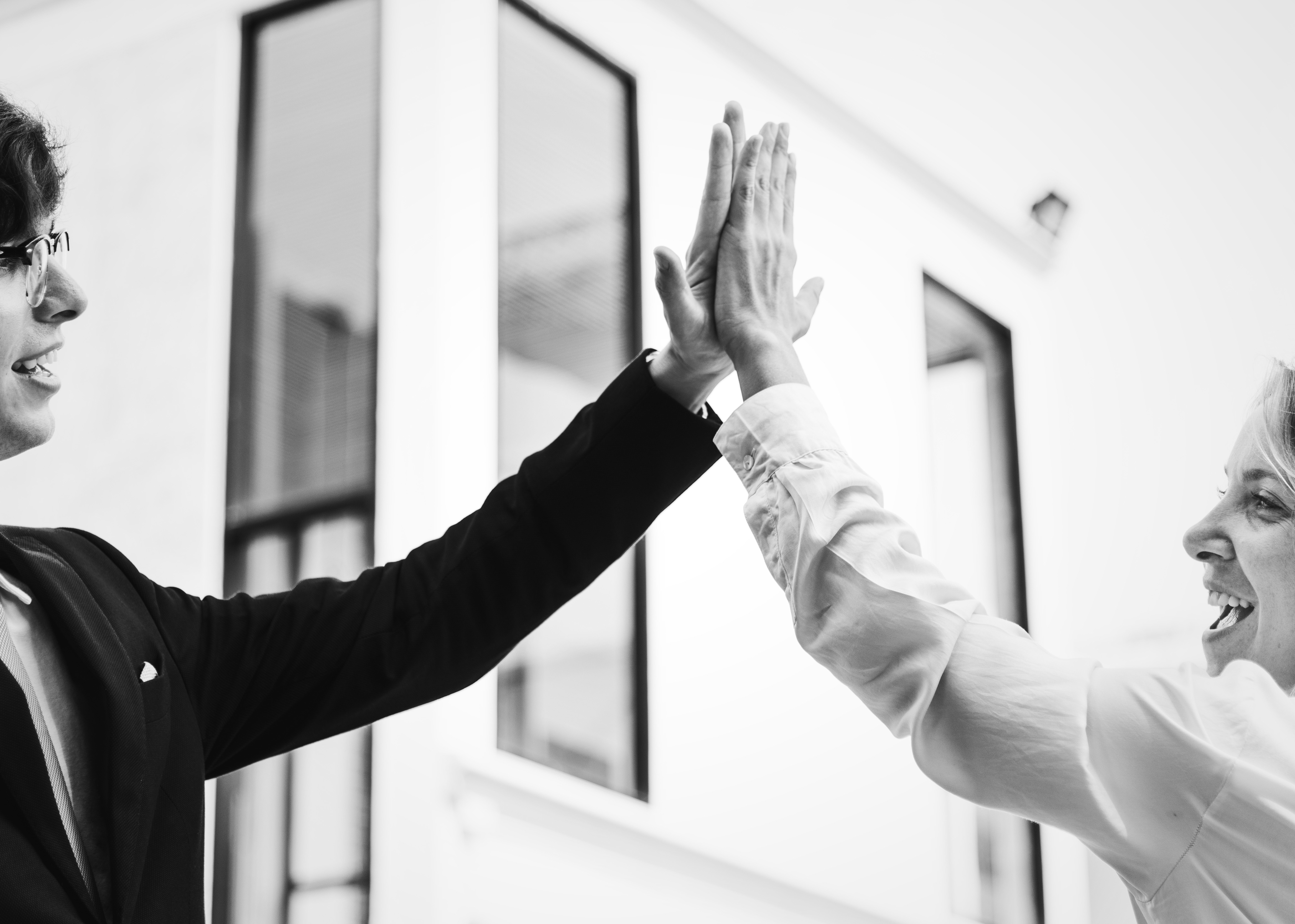 two people doing a high five in black and white