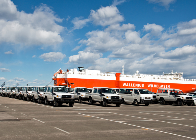 TGS trucks parked at port with cargo ship in the background