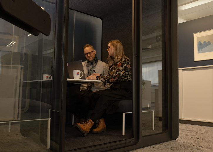 Two people sitting in a meeting pod
